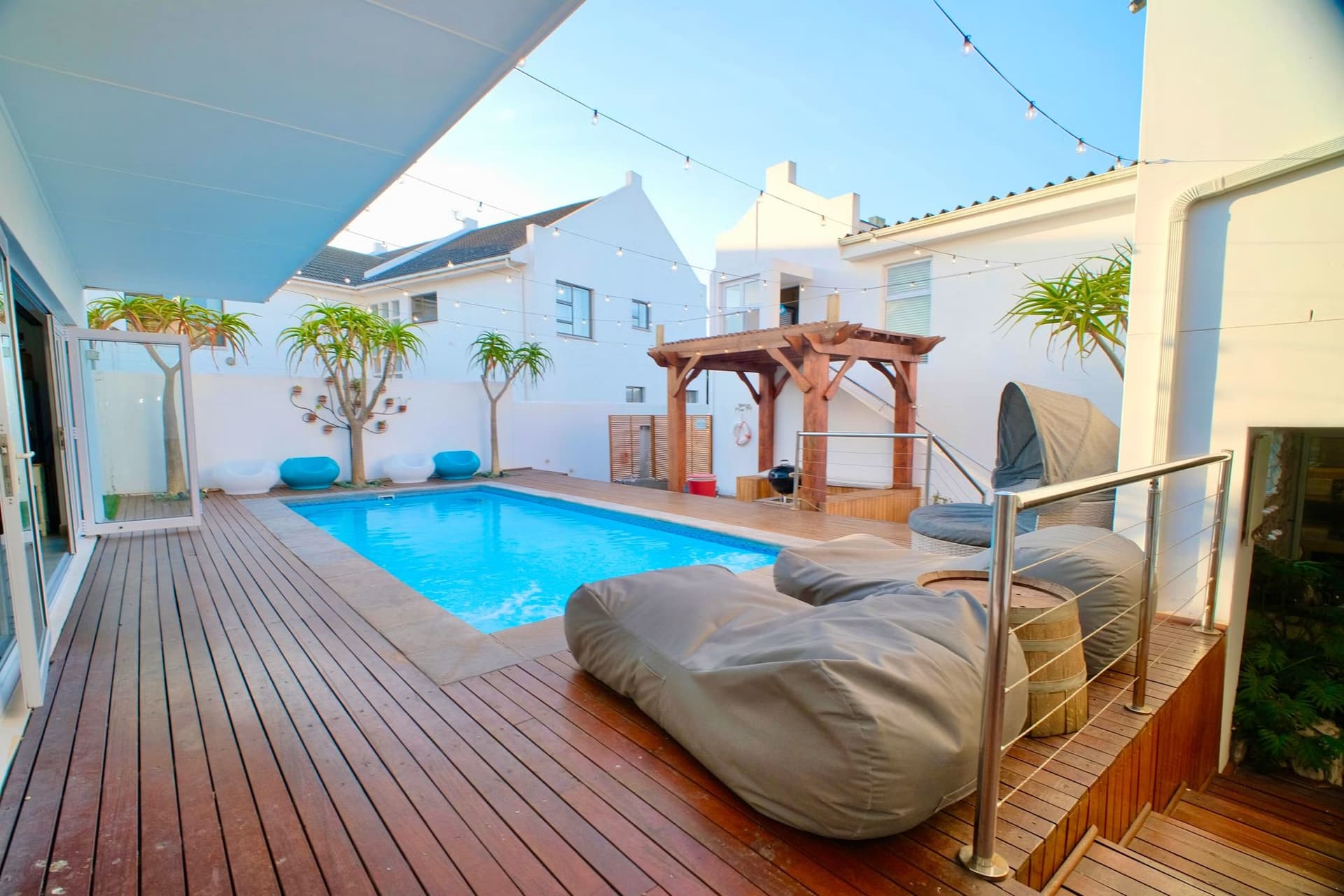 The pool deck by day with bean bag loungers and the whitewashed house behind